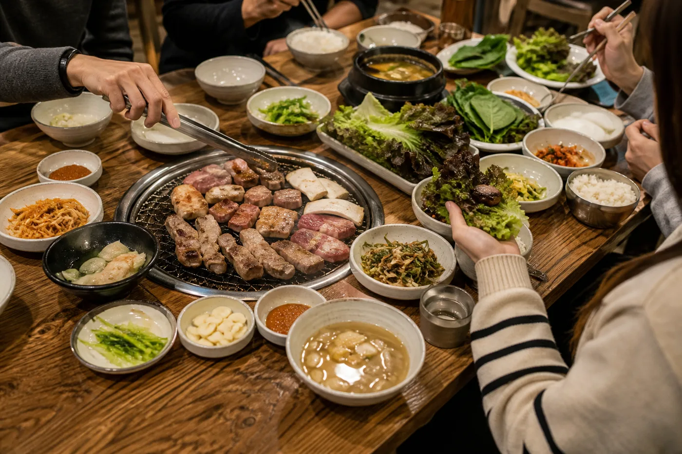 주말 외식 자리, 고기 구이와 여러 가지 반찬이 푸짐하게 차려진 한국 식당 테이블에 둘러앉은 사람들 — 주말 약속과 외식이 겹치면 식사량이 늘어나기 쉬움, 고양 향동 경희미르애한의원 늘씬다이어트 칼럼